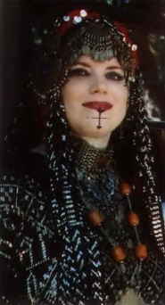 Izora's facial tattoos, jewelry, and headdress are very typical of the American tribal style.